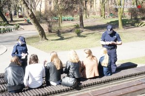 Policjanci i młodzież siedząca na ławkach