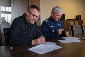 zdjęcie przedstawia zastępcę komendanta i mężczyznę podpisującego dokumenty