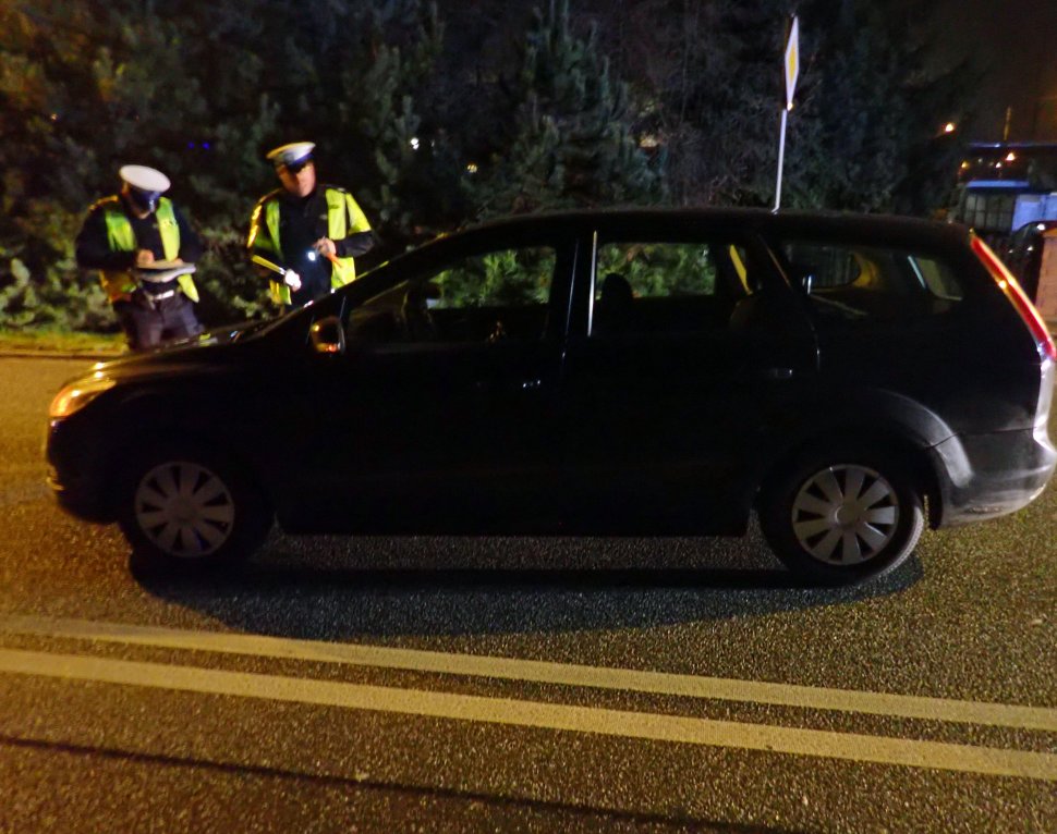 Policjanci prowadzą oględziny miejsca wypadku drogowego.