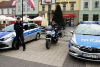 chłopiec siedzi przydem na motocyklu obok policjan i radiowozy