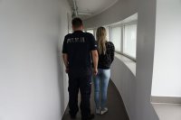 Fotografia kolorowa. Zatrzymana kobieta i umundurowany funkcjonariusz Policji.