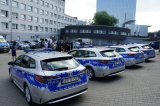 zdjęcie 4 radiowozów z tyłu. w tle policjanci i samorządowcy