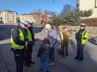 Policjanci i licealiści rozdają odblaski.