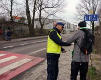 Policjant wręcza opaskę odblaskową pieszemu.