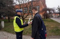 Policjant wręcza odblask mężczyźnie.