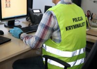 Policjant kryminalny wykonuje zdjęcia sygnalityczne podejrzanego.