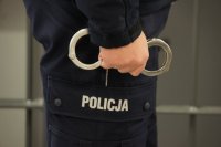 Policjant trzymający w ręku kajdanki