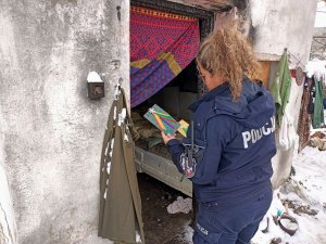 Policjantka wręcza bezdomnemu świąteczną kartkę.