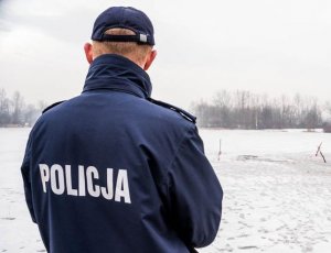 Policjant patrzący w kierunku zamarzniętego zbiornika wodnego.