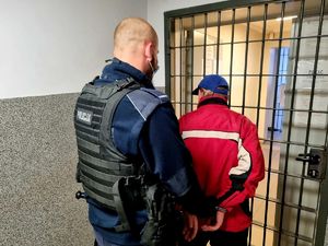 Policjant zakłada kajdanki zatrzymanemu 55-latkowi.