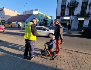 Policjant wręcza dziecku odblask.