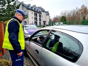 Policyjna kontrola. Policjant legitymuje kierującego osobówką. Działania z wykorzystaniem drona.