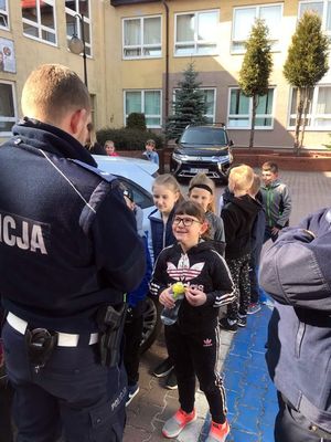 Policjant rozmawia z dziećmi o bezpieczeństwie podczas drogi do szkoły.