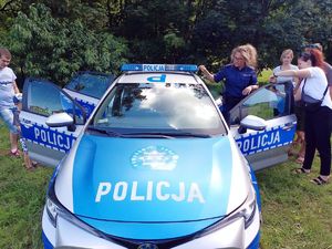 Rybnicka policjantka prezentuje dzieciom policyjny radiowóz.
