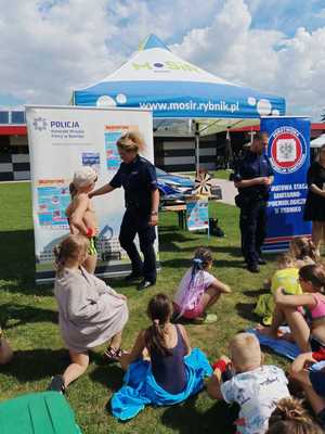 Policjantka rozmawia z dziećmi na temat bezpiecznych zachowań podczas wakacji.
