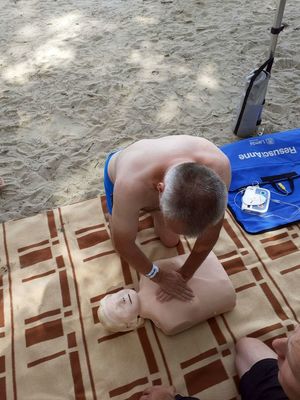 Mężczyzna podczas ćwiczeń na manekinie prowadzi resustytację krążeniowo - oddechową.