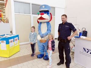 Policjant, policyjna maskotka Sznupek wraz z dzieckiem podczas pamiątkowego zdjęcia.