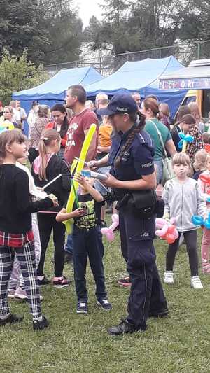 Policjantka na festynie rodzinnym rozdaje dzieciom odblaski.