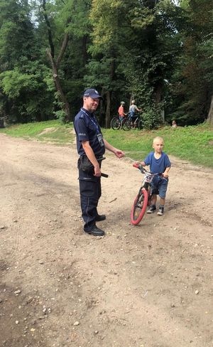 Policjant z chłopcem na rowerku podczas działań.