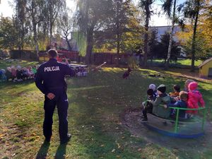 Policjant rozmawia z dziećmi na temat bezpieczeństwa w domu i podczas zabaw.