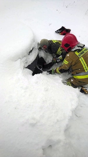 Akcja ratownicza, strażacy wyciągają mężczyznę ze studzienki.