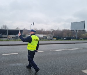 Umundurowany policjant zatrzymuje kierowcę osobówki.