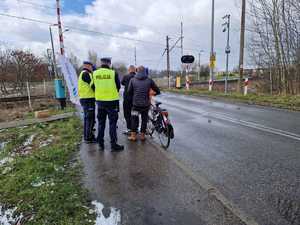 Policjanci rozmawiają z rowerzystami na temat bezpiecznego przejazdu przez przejazd kolejowy