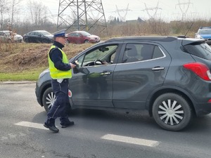 Mundurowy sprawdza alkomatem trzeźwość kierującego.