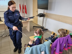 Policjantka rozdaje dzieciom odblaski.