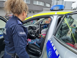 Policjantka pokazuje najmłodszym policyjny radiowóz.