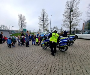 Przedszkolaki na terenie komendy w Rybniku oglądają radiowóz oraz motocykle.