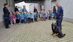 Policjant prezentuje dzieciom  zachowania i umiejętności swego psa.