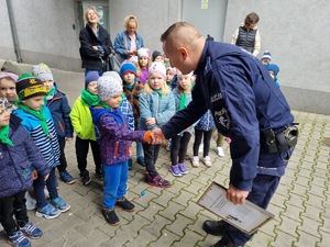 Dzieci wręczają policjantowi rysunek.