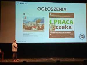 Policjant podczas konferencji prezentuje oferty pracy, pod które podszywają się oszuści.