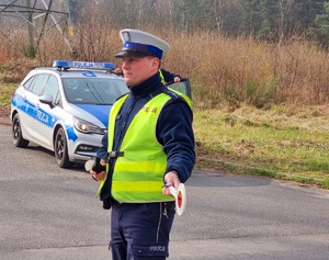 Policjant zatrzymujący pojazd osobowy.