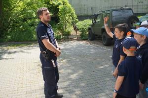 Policjant przekazuje dzieciom rady dotyczące bezpieczeństwa na ulicy.