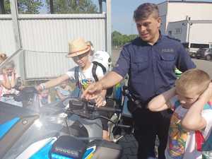 Policjant prezentuje dzieciom policyjny motocykl.