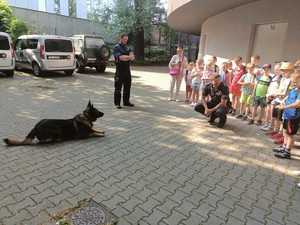 Policjant tłumaczy dzieciom specyfikę swojej służby, którą pełni wraz ze swoim psem służbowym.