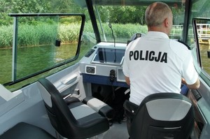 Policjant za sterem łodzi motorowodnej.