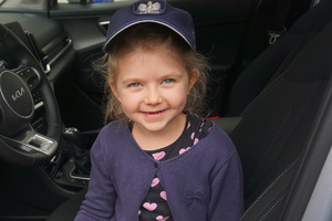 Uśmiechnięta dziewczynka w czapce policyjnej.