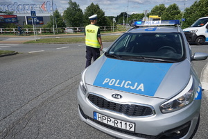 Policjant ruchu drogowego, w rejonie skrzyżowania o ruchu okrężnym kieruje ruchem.