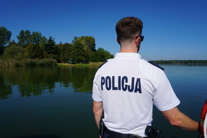 Policjant patrzy na linię brzegu w rejonie Zalewu Rybnickiego.