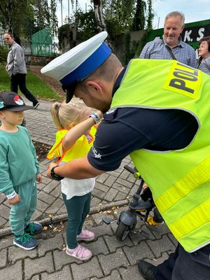 Policjant wręcza dziecku kamizelkę odblaskową.