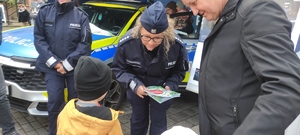 Policjanta wręcza ulotkę młodemu mieszkańcowi miasta.