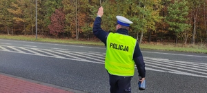 Policjant, który daje znak do zatrzymania się kierującemu.