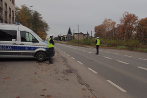 Na zdjęciu policjant stoi na środku drogi z urządzeniem do badania stanu trzeźwości.