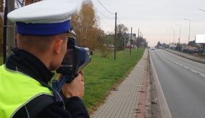 Na zdjęciu policjant, który korzysta z urządzenia do pomiaru prędkości.