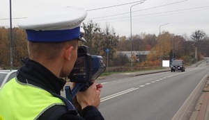 Na zdjęciu policjant, który mierzy prędkość nadjeżdżającego pojazdu.