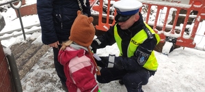 Policjant wręcza odblask dziecku.