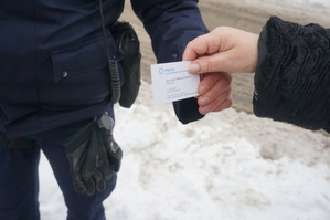 Policjant wręcza swoją wizytówkę kobiecie.